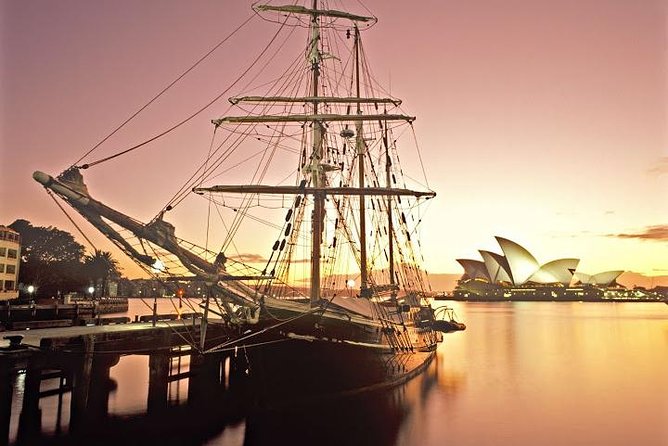 A tall ship crossing Sydney Harbour past the Opera House at sunset